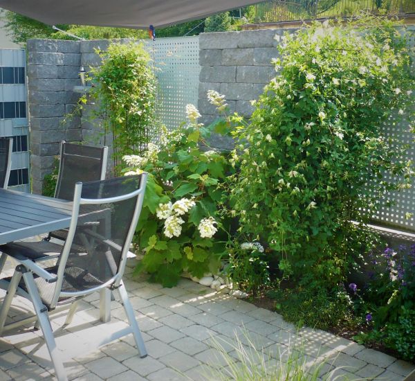 Gartenmauer aus Pflastersteinen und Metall als Sichtschutz